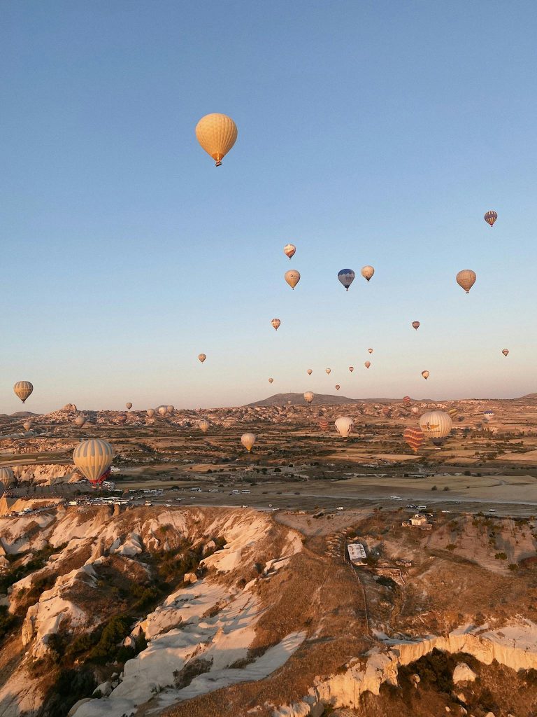 A breathtaking view of hot air balloons soaring over Cappadocia during sunrise in Göreme, Turkey.