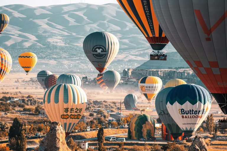 Stunning view of colorful hot air balloons flying over Cappadocia's unique landscapes in Türkiye.