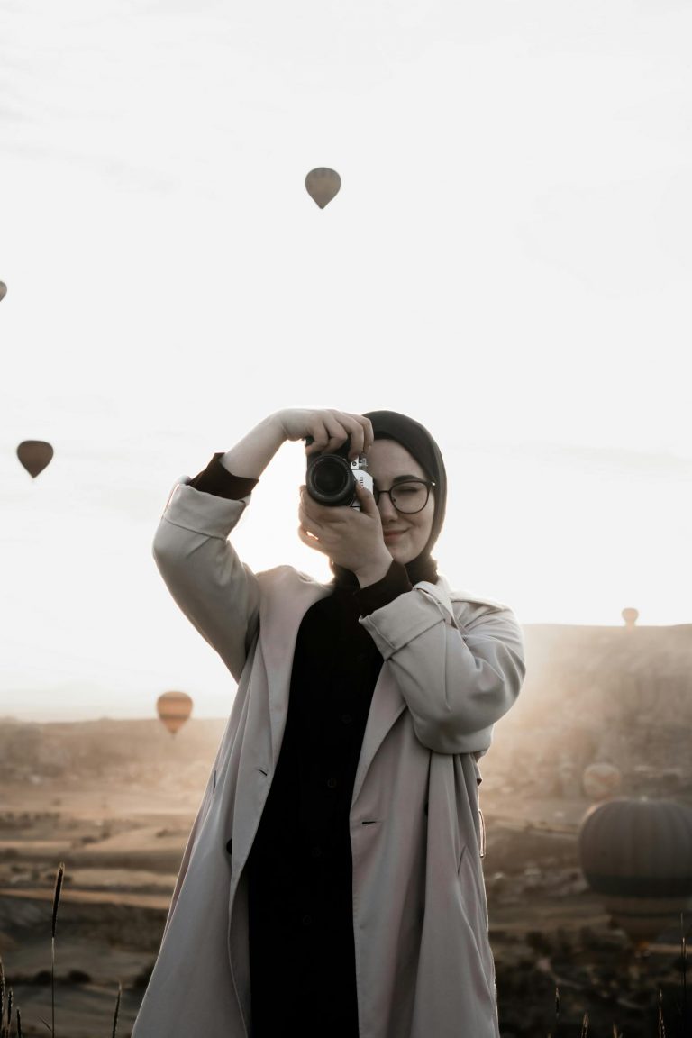 Young woman capturing stunning hot-air balloon view in Cappadocia.